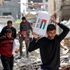 Người dân nhận hàng viện trợ nhân đạo tại Dải Gaza ngày 23/4/2024. (Ảnh: AFP/TTXVN)