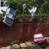 Một người đàn ông ở Hải Khẩu, tỉnh Hải Nam, Trung Quốc nhìn vào chiếc xe bị mắc kẹt trong 'hố tử thần' với ánh mắt vô vọng. (Nguồn: Reuters)