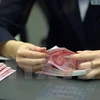 Nhân viên ngân hàng kiểm tiền 100 nhân dân tệ mới tại một ngân hàng ở thủ đô Bắc Kinh ngày 12/11. (Nguồn: THX/TTXVN)