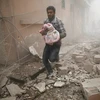 Người đàn ông bế một em bé sơ sinh chạy trên đường phố ở thị trấn Douma do phiến quân chiếm đóng, gần thủ đô Damascus. (Nguồn: Anadolu)