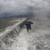Một người dân ở huyện Albay cố chạy khỏi những con sóng do bão Melor gây ra. (Nguồn: AFP)