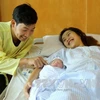 Vợ chồng sản phụ Phạm Thị Hồng Loan hạnh phúc bên cháu bé. (Ảnh: Trung Kiên/TTXVN) 