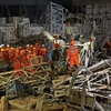 Nhân viên cứu hộ tìm kiếm những người bị mắc kẹt trong đống đổ nát sau vụ sập ngày 24/11. (Nguồn: THX/TTXVN)