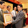 Đồng chí Nguyễn Đức Lợi, Tổng Giám đốc TTXVN trao bằng khen cho các Cựu Chiến binh TTXVN. (Ảnh: TTXVN)