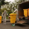 Tại mỗi điểm lấy rác, công nhân đều tiến hành phun khử khuẩn trước khi thu gom. (Ảnh: CTV/Vietnam+)