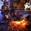 Các e nhỏ ngồi nhóm lửa sưởi ấm trên phố Nguyễn Thái Học, Hà Nội. (Ảnh: Thành Đạt/TTXVN)