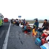 Người dân ngồi la liệt, thành hàng dài dọc đường để bắt xe khách. (Ảnh: Minh Sơn/Vietnam+)