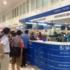 Rất đông hành khách bị hủy chuyến bay tập trung trước quầy làm thủ tục để nhận được lời giải thích từ VASCO. (Ảnh: Phạm Anh Tuấn/Vietnam+)