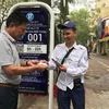 Khách hàng nhận hóa đơn từ nhân viên trông giữ phương tiện tại điểm đỗ sử dụng công nghệ iParking trên phố Lý Thường Kiệt. (Ảnh: Việt Hùng/Vietnam+)