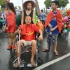 ông Đinh Anh Tuấn ở Sóc Sơn, Hà Nội vẫn "vịn" xe lăn xuống đường đón đoàn thể thao Việt Nam. (Ảnh: Sơn Bách/Vietnam+)