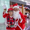 Hành khách nhí chụp hình và nhận món quà từ Ông già Noel của Cảng hàng không Nội Bài. (Ảnh: Dương Phạm/Vietnam+)