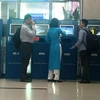 Nhân viên Vietnam Airlines hướng dẫn khách làm thủ tục trực tuyến tại kiosk check-in. (Ảnh: Việt Hùng/Vietnam+)
