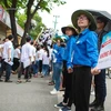 Sinh viên tình nguyện của trường Đại học Kinh tế quốc dân đứng sát nhau tạo thành hàng rào giúp các thí sinh nhanh chóng rời trường sau giờ thi. (Ảnh: Minh Sơn/Vietnam+)