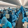 Tất cả hành khách được phát và phải mặc đồ bảo hộ trong suốt chuyến bay từ nước ngoài - nơi có dịch COVID-19 về Việt Nam. (Ảnh: CTV/Vietnam+)