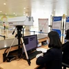 Nhân viên kiểm dịch y tế do thân nhiệt hành khách tại sân bay Nội Bài. (Ảnh: Phan Công/Vietnam+)