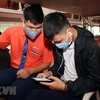 Hành khách tại bến xe Nước Ngầm (Hà Nội), được nhân viên nhà xe hướng dẫn khai báo y tế trên ứng dụng điện thoại. (Ảnh: Danh Lam/TTXVN)