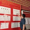 Cử tri xem xét danh sách niêm yết những người ứng cử đại Quốc hội khóa XV và Hội đồng Nhân dân các cấp nhiệm kỳ 2021-2026. (Ảnh: Xuân Quảng/Vietnam+)