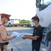 Cảnh sát giao thông kiểm tra giấy tờ của lái xe trước khi vào địa phương. (Ảnh: CTV/Vietnam+)