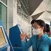 Nhân viên Vietnam Airlines hướng dẫn giúp hành khách làm thủ tục trực tuyến tại Kios check-in online ở một sân bay. (Ảnh: CTV/Vietnam+)