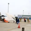 Các lực lượng tham gia diễn tập khống chế và dập đám cháy sau sự cố tràn nhiên liệu từ máy bay. (Ảnh: CTV/Vietnam+)