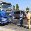 Tổ cảnh sát giao thông kiểm tra chủ phương tiện điều khiển xe trên Quốc lộ 1 thuộc huyện Châu Thành, tỉnh Tiền Giang. (Ảnh: Minh Trí/TTXVN)