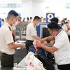 Nhân viên an ninh hàng không kiểm tra hành lý xách tay hành khách tại điểm soi chiếu. (Ảnh: CTV/Vietnam+)