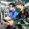 Đăng kiểm viên quân đội phối hợp với nhân viên đăng kiểm thực hiện quy trình kiểm định xe cơ giới. (Ảnh: Hoài Nam/Vietnam+)