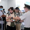 Nhân viên an ninh hàng không sân bay Nội Bài kiểm tra giấy tờ hành khách làm thủ tục đi máy bay. (Ảnh: PV/Vietnam+)