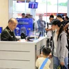 Nhân viên an ninh hàng không kiểm tra giấy tờ hành khách làm thủ tục chuyến bay. (Ảnh: PV/Vietnam+)