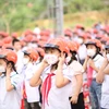 Hướng dẫn học sinh tiểu học đội mũ bảo hiểm khi tham gia giao thông. (Ảnh: PV/Vietnam+)