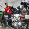 Nhân viên kiểm tra khí thải tại một cơ sở bảo dưỡng, sửa chữa xe máy. (Ảnh: Tuấn Đức/TTXVN)