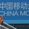 Một người sử dụng iPhones 5s đứng trước biển quảng cáo China Mobile ở Thượng Hải (Nguồn: TTXVN)