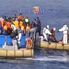 Lực lượng hải quân Italy chuyển người di cư xuống tàu cứu hộ (trái và phải) ngoài khơi Libya. (Nguồn: AFP/TTXVN