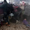 Người di cư chạy trốn hơi cay do cảnh sát Macedonia sử dụng nhằm ngăn dòng người bạo động đang tìm cách phá hàng rào biên giới. (Nguồn: AFP/TTXVN)