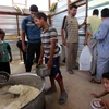 Trẻ em Iraq xếp hàng nhận lương thực cứu trợ tại khu vực Dora, ngoại ô thủ đô Baghdad ngày 31/5, sau khi phải rời bỏ nhà cửa ở khu vực chiến sự. (Nguồn: AFP/TTXVN)