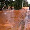 Nước bùn đỏ chảy tràn ra đường sau khi hồ chứa nước thải titan tại Bình Thuận bị vỡ hồi tháng 11/2013. (Ảnh Nguyễn Thanh/TTXVN)