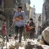 Sơ tán các em nhỏ Syria ra khỏi một tòa nhà bị sập sau vụ không kích nhằm ở thành phố Aleppo. (Nguồn: AFP/TTXVN)