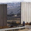 Những người dân Palestine đi bộ gần hàng rào gây tranh cãi của Israel ở phía đông khu phố Jerusalem của A-tur. (Nguồn: Reuters)
