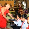 Các nhà sư trao quà cho các học sinh nghèo vượt khó tại chùa Bàng Long ở thủ đô Vientiane, Lào. (Ảnh: Phạm Kiên/TTXVN)