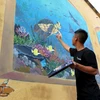Các tình nguyện viên đang hoàn thiện những nét vẽ cuối cùng trên đảo Bé. (Ảnh: Phước Ngọc/TTXVN)