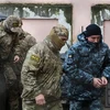 Nhân viên mật vụ thuộc Cơ quan An ninh Liên bang Nga áp giải một thủy thủ Ukraine (phải) bị bắt tới tòa án ở Simferopol, Bán đảo Crimea ngày 27/11/2018. (Ảnh: AFP/TTXVN)