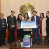 Ông Nguyễn Phương Sơn, Giám đốc Đối ngoại Amway Việt Nam trao biển tượng trưng số tiền tài trợ cho đại diện Báo Điện tử Chính phủ. (Ảnh: PV/Vietnam+)