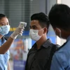 Một nhân viên kiểm tra thân nhiệt cho người dân tại Yangon, Myanmar nhằm ngăn chặn sự lây lan của dịch COVID-19, ngày 13/3/2020. (Ảnh: THX/TTXVN)