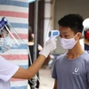 Nhân viên y tế kiểm tra, đo thân nhiệt cho người dân thôn Hạ Lôi, Hà Nội sau khi thôn được cách ly đề phòng lây nhiêm COVID-19. (Anh: Minh Quyết/TTXVN)