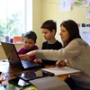 Một gia đình ở Anh giúp con học trực tuyến do các trường học phải đóng cửa vì dịch COVID-19. (Ảnh: AFP/TTXVN)