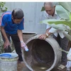 Người dân thau rửa các dụng cụ chứa nước để diệt bọ gậy. (Ảnh: Xuân Triệu/TTXVN)