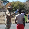 Bính lính Nam Phi thực hiện đo thân nhiệt cho người dân tại ngoại ô thủ đô Pretoria. (Ảnh: Phi Hùng/TTXVN)