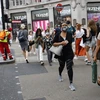 Người dân đeo khẩu trang phòng lây nhiễm COVID-19 khi di chuyển trên đường phố tại London. (Ảnh: AFP/TTXVN)