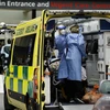 Nhân viên y tế chuyển bệnh nhân COVID-19 tới bệnh viện tại London, Anh. (Ảnh: AFP/TTXVN)