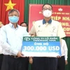Chủ tịch UBND tỉnh Đồng Nai Cao Tiến Dũng (trái) tiếp nhận 300.000 USD từ Đại diện Công ty cổ phần Taekwang Vina ủng hộ Quỹ vaccine phòng, chống dịch COVID-19. (Ảnh: TTXVN phát)